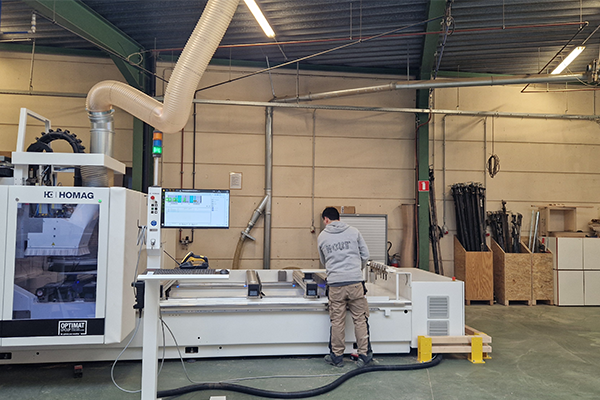 A man operates a machine in a factory, focused on his task amidst industrial surroundings.