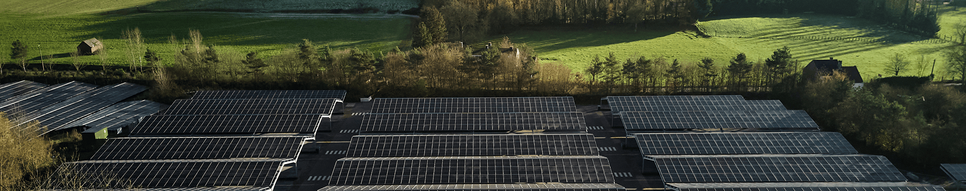 Aerial view of a solar farm featuring rows of solar panels under a clear blue sky.