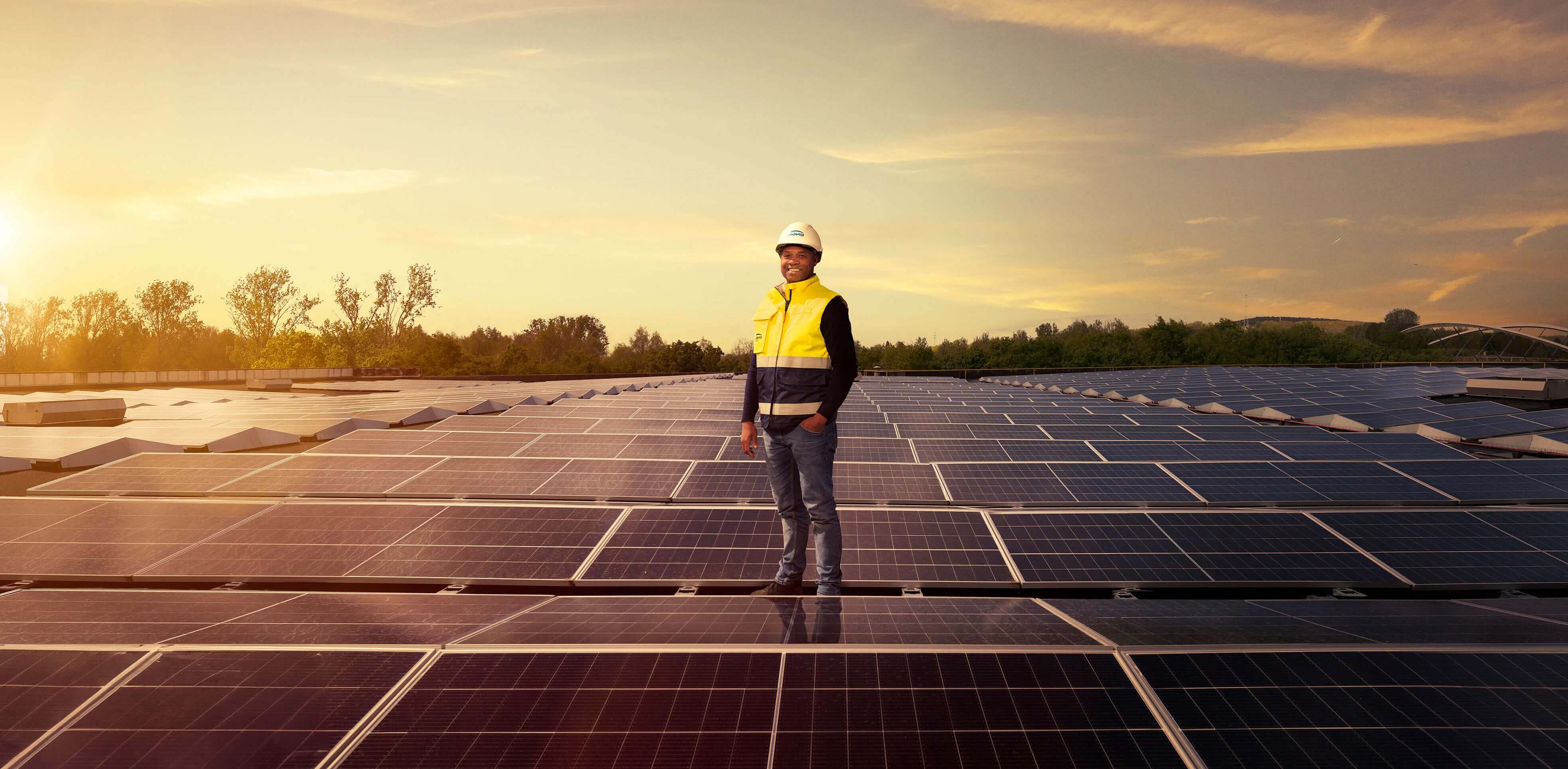 ENGIE employee on a rooftop with solar panels at sunset