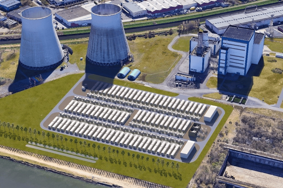 Vue aérienne d'une centrale électrique avec deux tours de refroidissement et une série de structures rectangulaires blanches alignées sur la pelouse adjacente.